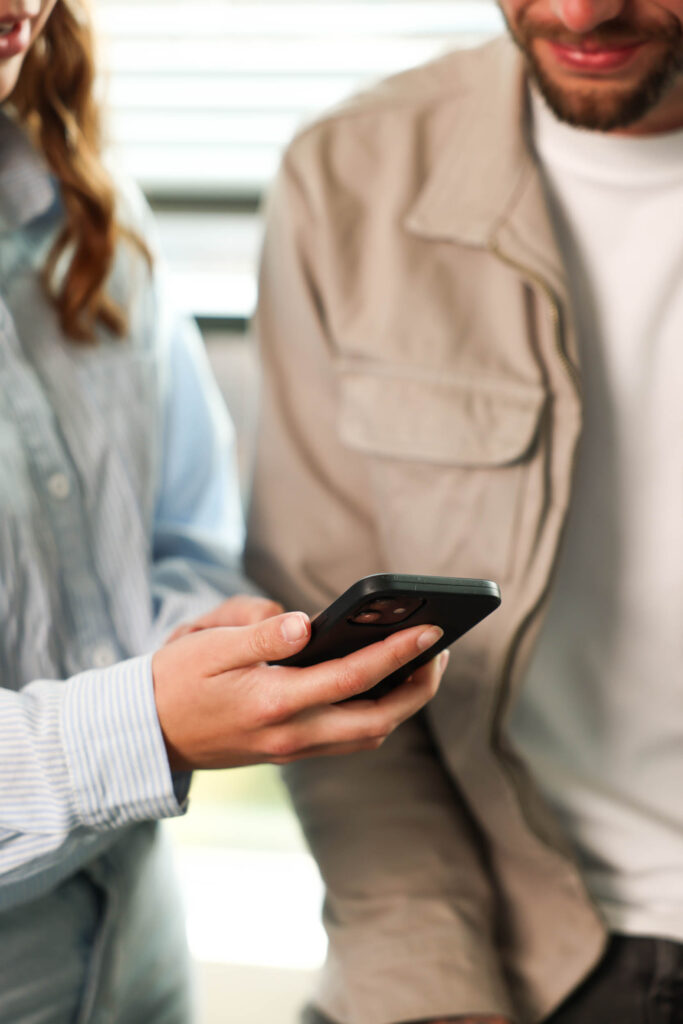 Twee personen waarvan één telefoon in handen heeft