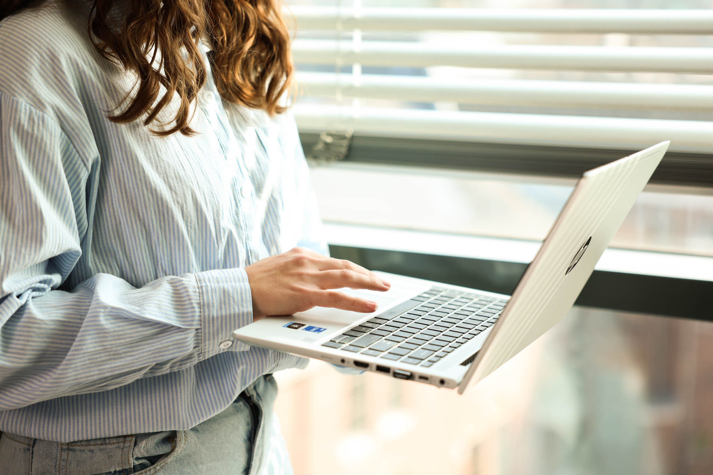 Persoon met laptop bij raam